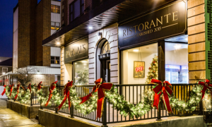 Restaurant exterior decorated with holiday lights and red bows at night; Christmas tree and neon