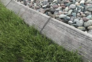 Close-up view of a border separating green grass on the left from a section of variously colored rocks on the right, perfect for a Showcase Gallery display.