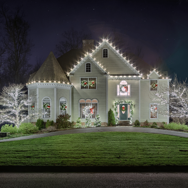 Homeowner struggling to hang tangled Christmas lights on a ladder in winter